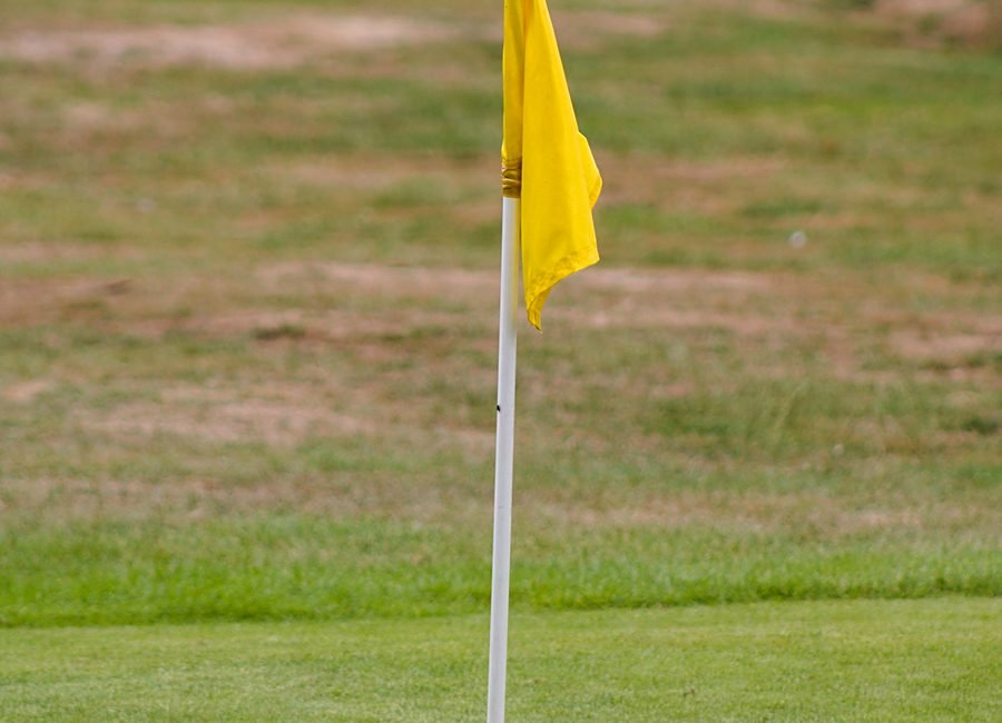 Golfer practicing a chip shot near the edge of the green