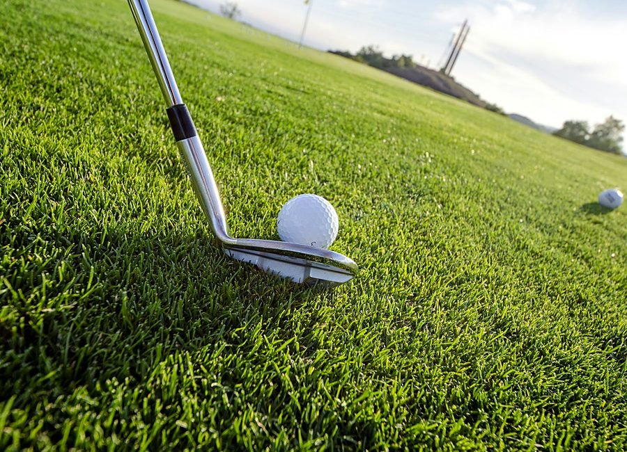 A golf coach guiding a student through their stance during a lesson