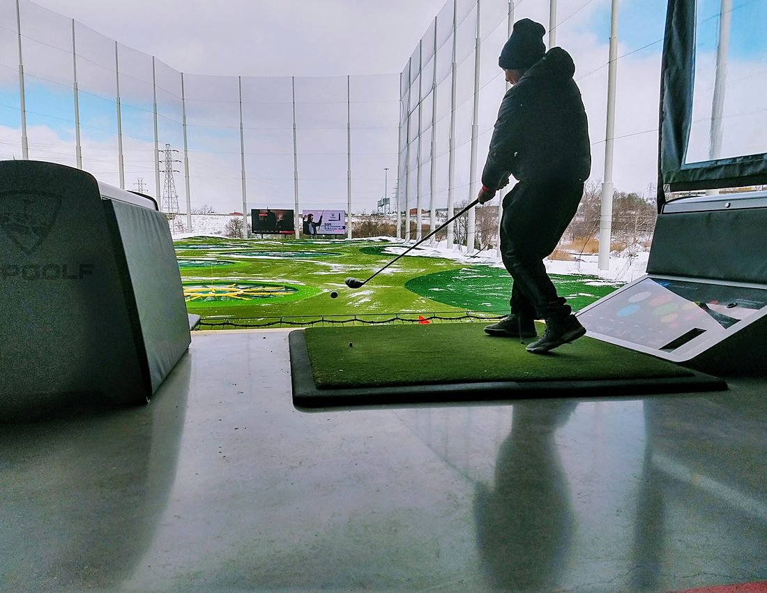 Indoor golf simulator bay with a large projection screen