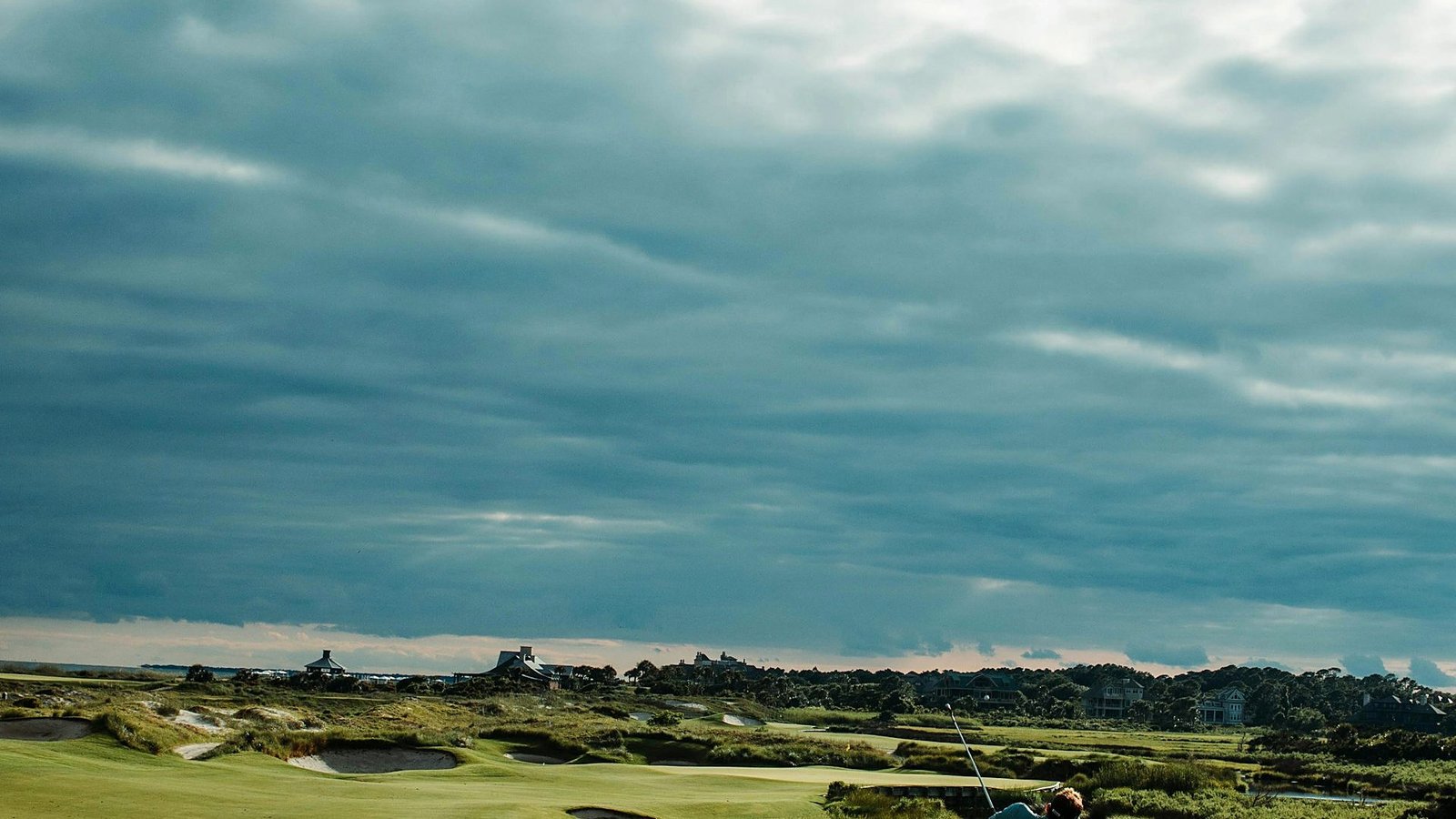 A golfer completing a full swing on the fairway at Greenmere Golf & Country Club at golden hour