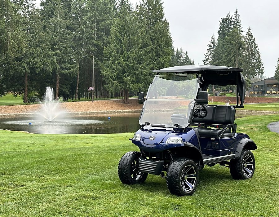 A golf cart parked beside the practice green on a misty morning
